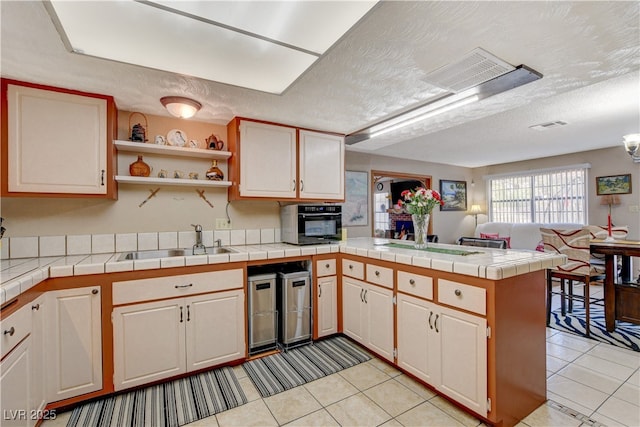 611 Spyglass Ln, Las Vegas, NV 89107 - kitchen featuring a sink, a textured ceiling, a peninsula, open floor plan, and light tile patterned floors