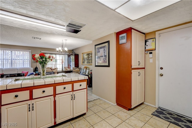 611 Spyglass Ln, Las Vegas, NV 89107 - kitchen featuring visible vents, tile countertops, light tile patterned floors, and an inviting chandelier
