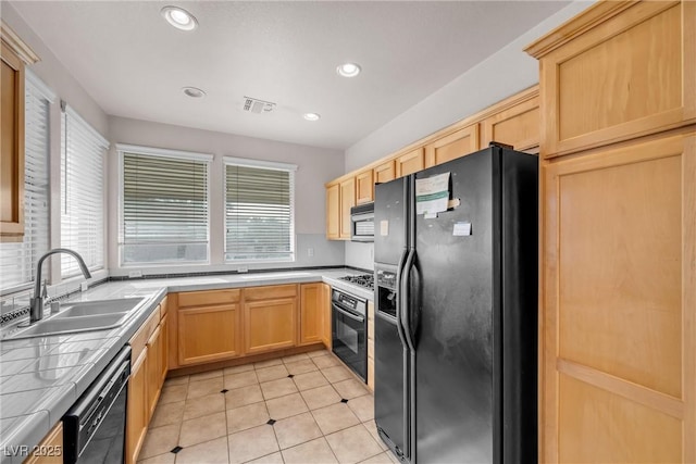 kitchen with visible vents, a sink, black appliances, light brown cabinets, and tile counters
