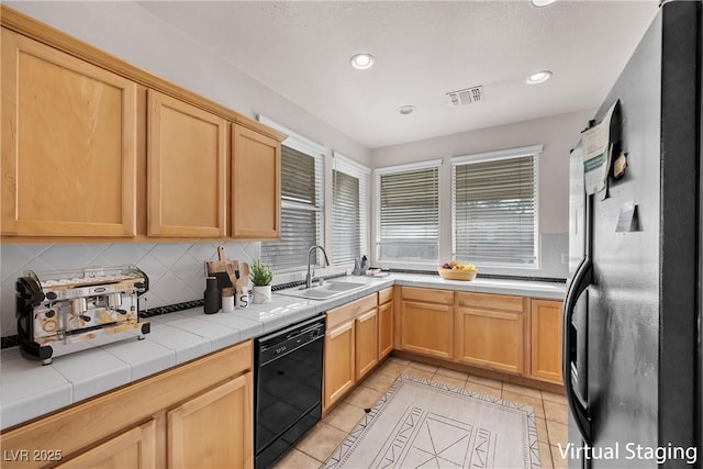 kitchen featuring visible vents, light brown cabinetry, a sink, light tile patterned floors, and black appliances