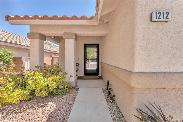 doorway to property featuring fence and stucco siding