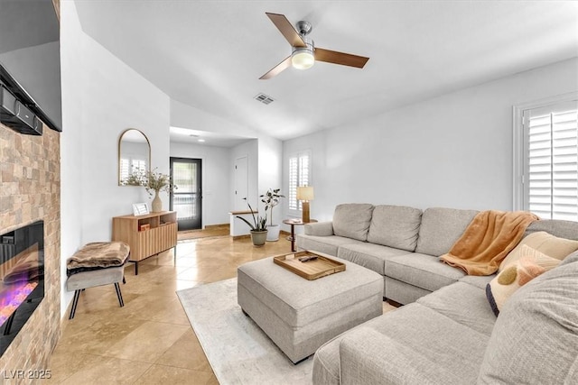 living room featuring light tile patterned flooring, a glass covered fireplace, a ceiling fan, vaulted ceiling, and visible vents