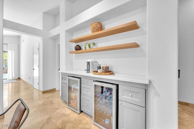 bar featuring wine cooler, bar area, baseboards, and light tile patterned flooring