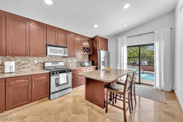 kitchen with a breakfast bar area, stainless steel appliances, recessed lighting, decorative backsplash, and lofted ceiling
