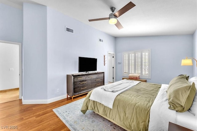 bedroom with baseboards, ceiling fan, wood finished floors, and visible vents