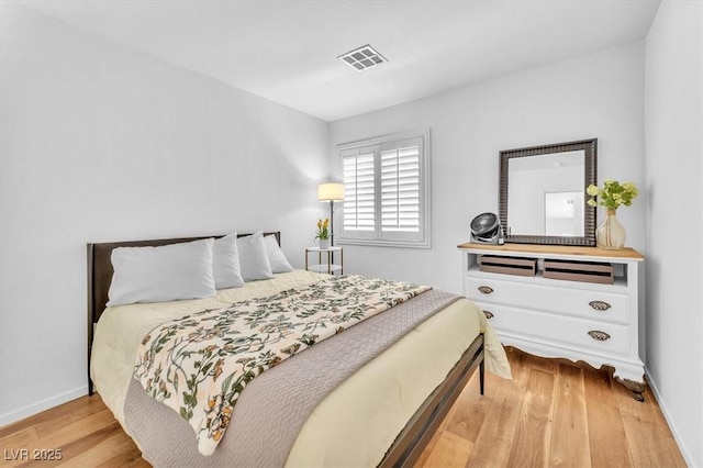 bedroom with baseboards, wood finished floors, and visible vents
