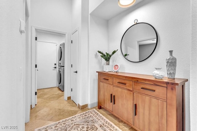 bathroom with baseboards, stacked washer and clothes dryer, and vanity