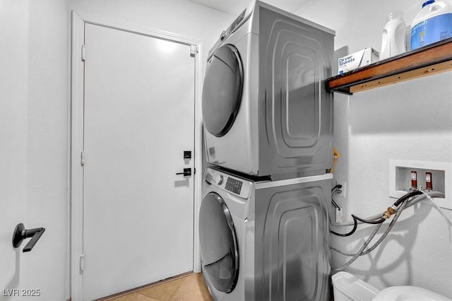 washroom with laundry area, stacked washer and dryer, and light tile patterned flooring