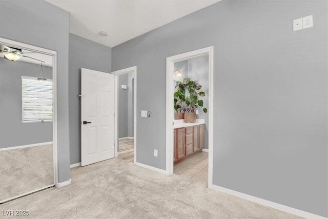 unfurnished bedroom with connected bathroom, baseboards, light colored carpet, and a closet