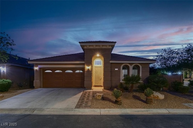 mediterranean / spanish home with an attached garage, concrete driveway, a tile roof, and stucco siding