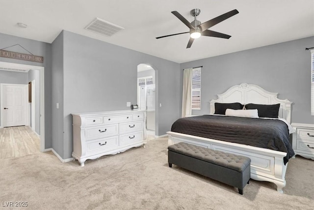 bedroom with visible vents, baseboards, ceiling fan, light colored carpet, and arched walkways