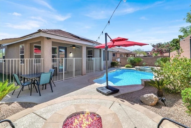 view of pool with a ceiling fan, a pool with connected hot tub, a fenced backyard, a patio, and a fire pit