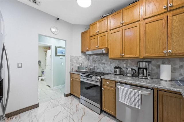 2725 Byron Dr, Las Vegas, NV 89134 - kitchen featuring appliances with stainless steel finishes, under cabinet range hood, decorative backsplash, light stone counters, and brown cabinetry