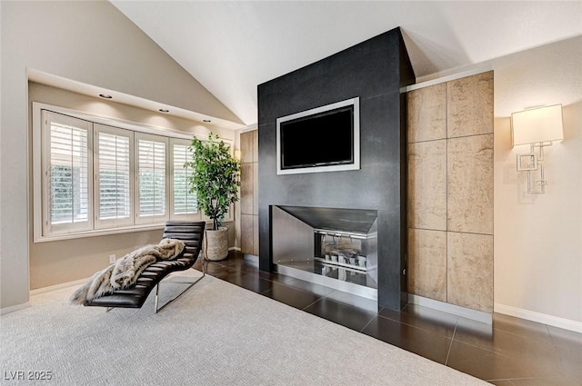 interior space featuring baseboards, a glass covered fireplace, and lofted ceiling
