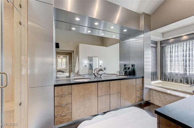 bathroom featuring double vanity, a sink, a bath, and recessed lighting