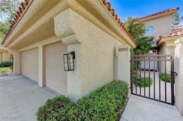 view of side of home featuring a garage, stucco siding, and a tile roof