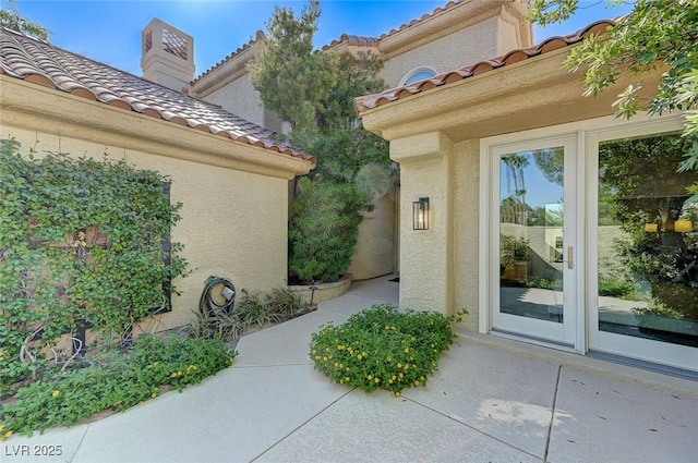 doorway to property with a tiled roof and stucco siding