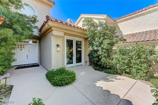 doorway to property featuring a tiled roof and stucco siding