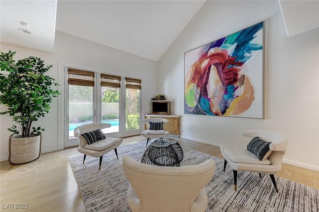 living room with baseboards, high vaulted ceiling, and light wood-style flooring