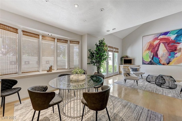 dining room with recessed lighting, a textured ceiling, wood finished floors, and lofted ceiling
