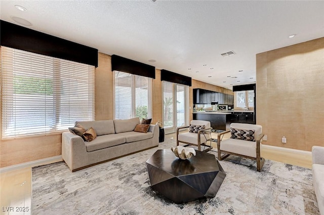 living area featuring baseboards, visible vents, and light wood-style flooring