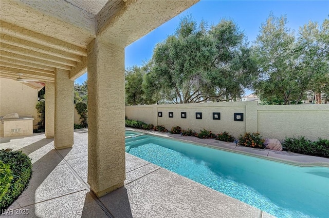 view of swimming pool featuring a fenced backyard, a patio, a pool with connected hot tub, and an outdoor kitchen