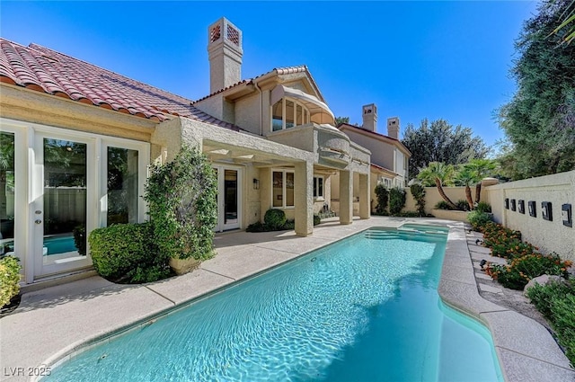 back of house featuring a fenced in pool, a fenced backyard, a tiled roof, and a patio