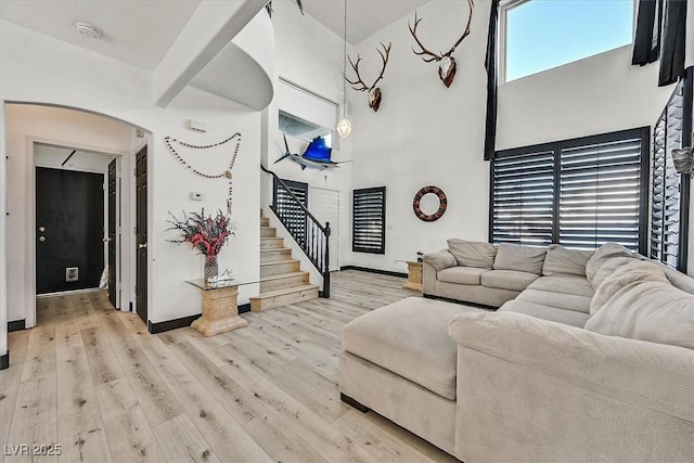3738 Falcon Springs Dr, Las Vegas, NV 89147 - living room with baseboards, a high ceiling, stairway, light wood-type flooring, and arched walkways