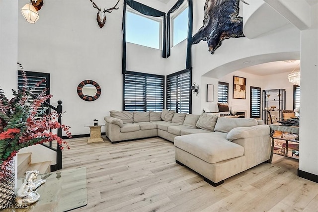 3738 Falcon Springs Dr, Las Vegas, NV 89147 - living area with a healthy amount of sunlight, arched walkways, wood finished floors, and a notable chandelier