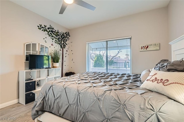 bedroom with light wood-type flooring, a ceiling fan, and baseboards