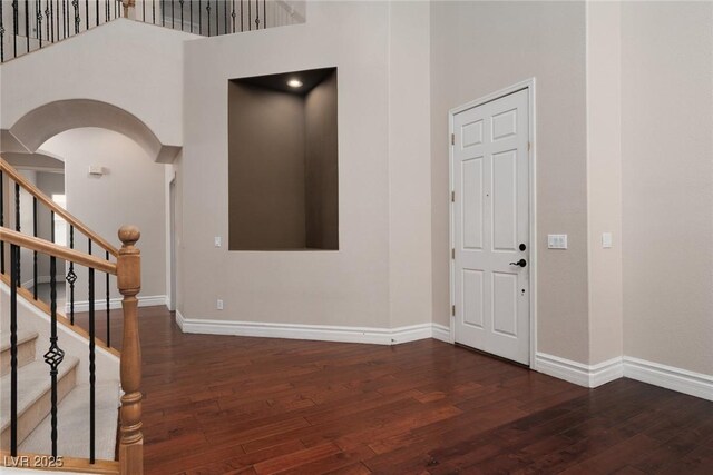 7736 Villa Andrade Ave, Las Vegas, NV 89131 - foyer featuring wood-type flooring, baseboards, a towering ceiling, arched walkways, and stairway