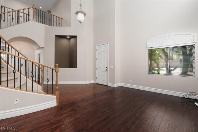 7736 Villa Andrade Ave, Las Vegas, NV 89131 - entrance foyer with hardwood / wood-style floors, a high ceiling, baseboards, arched walkways, and stairs