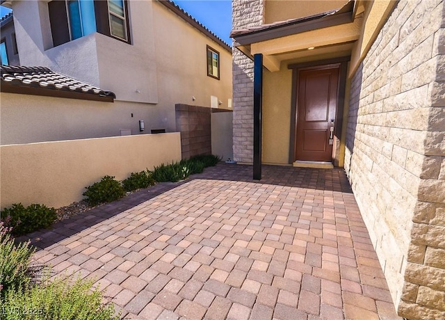 property entrance featuring fence, a patio area, and stucco siding