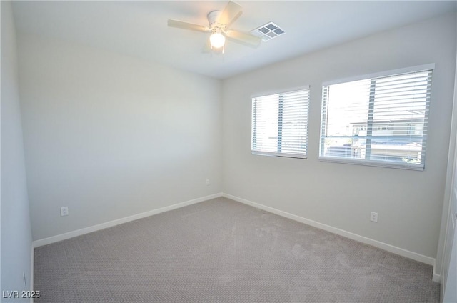 empty room featuring ceiling fan, visible vents, and baseboards