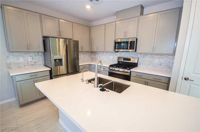 kitchen featuring stainless steel appliances, a sink, gray cabinets, and tasteful backsplash