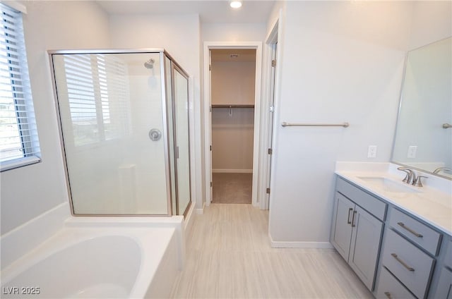 bathroom with vanity, a stall shower, a garden tub, and a walk in closet