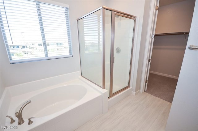 bathroom with a garden tub, a stall shower, and a spacious closet