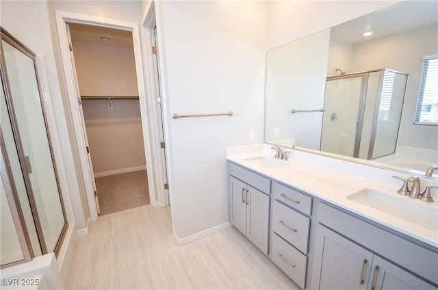 full bathroom with double vanity, a walk in closet, a sink, and a stall shower