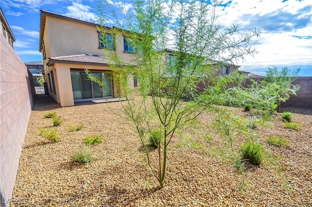 rear view of house featuring fence and stucco siding