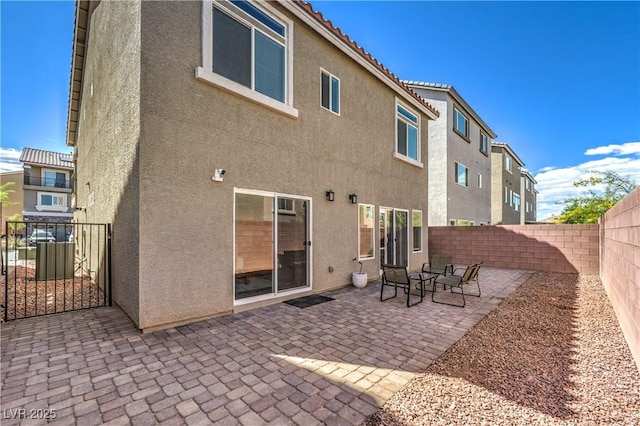 rear view of house featuring a fenced backyard, a patio area, stucco siding, and a gate