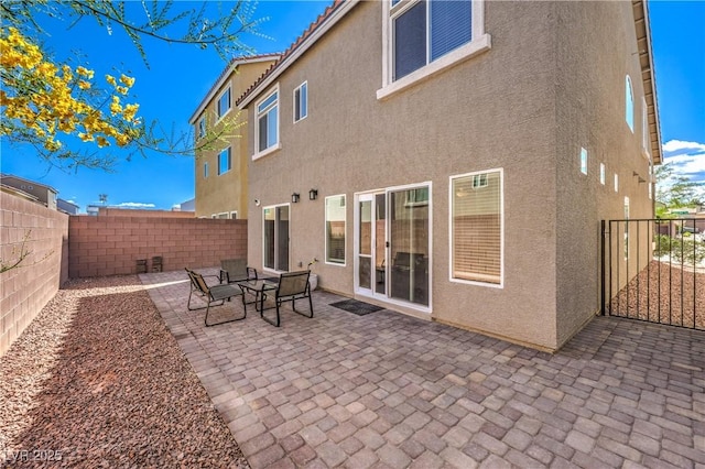 rear view of property with a patio, a fenced backyard, and stucco siding