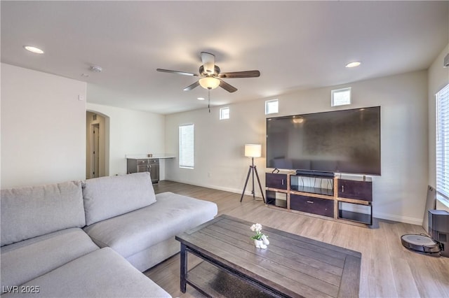 living room with arched walkways, plenty of natural light, a ceiling fan, and wood finished floors