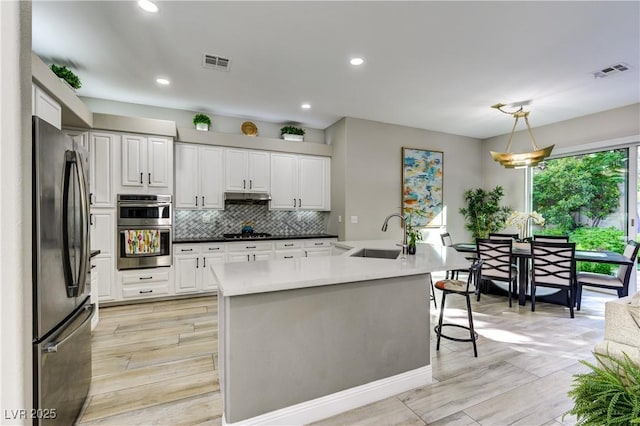 kitchen featuring a sink, appliances with stainless steel finishes, under cabinet range hood, and visible vents