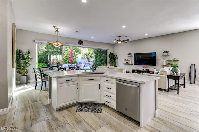 kitchen featuring dishwasher, a sink, light countertops, light wood-style floors, and white cabinetry