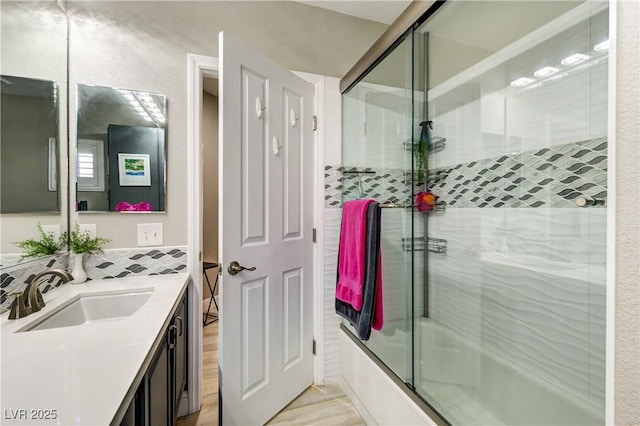 bathroom with enclosed tub / shower combo, decorative backsplash, and vanity