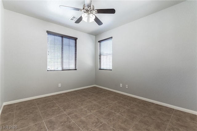 empty room with baseboards, ceiling fan, dark tile patterned floors, and visible vents