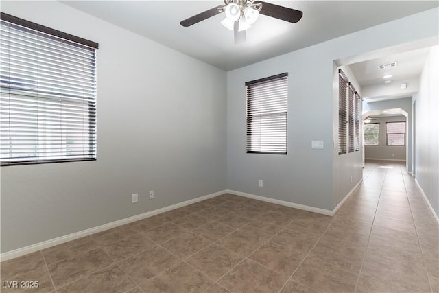 spare room featuring arched walkways, a ceiling fan, light tile patterned flooring, and visible vents