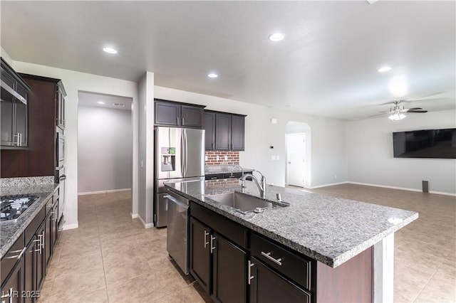 kitchen featuring ceiling fan, backsplash, arched walkways, a sink, and stainless steel appliances