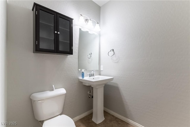 bathroom featuring baseboards, a sink, tile patterned flooring, and toilet