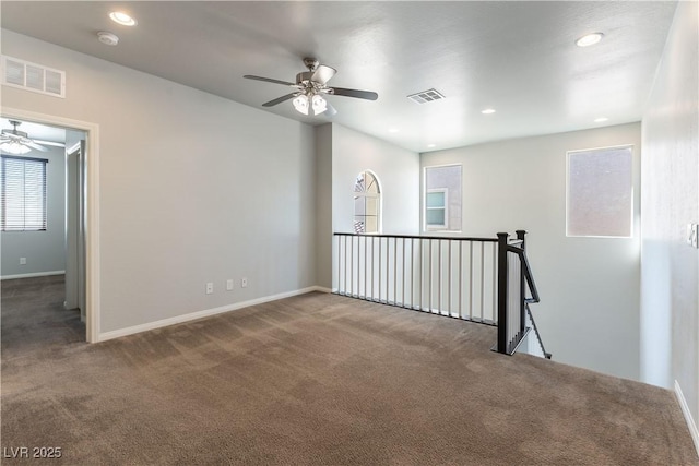 carpeted empty room with baseboards, ceiling fan, and visible vents